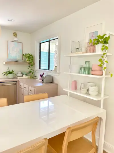 Witte CB2-ontbijttafel tegen witte wandplank met kommen en kopjes