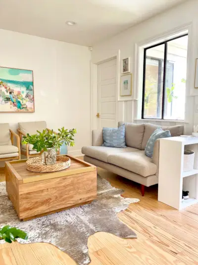 Zithoek in de keuken met grijze loveseat houten salontafel, koeienhuid vloerkleed en opbergkastje