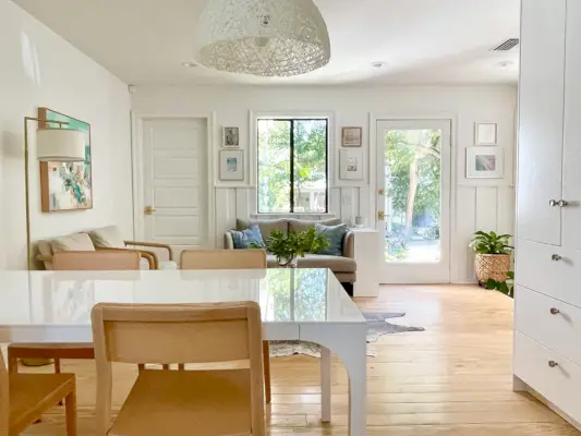 Uitzicht richting zithoek met witte moderne eettafel en houten stoelen