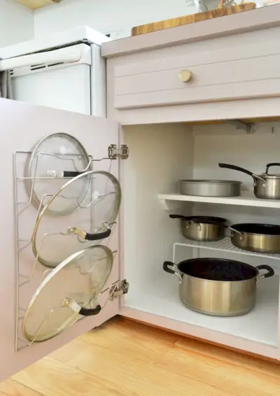 Potten en pannen georganiseerd in kleine keuken met deksel gemonteerd op kastdeur