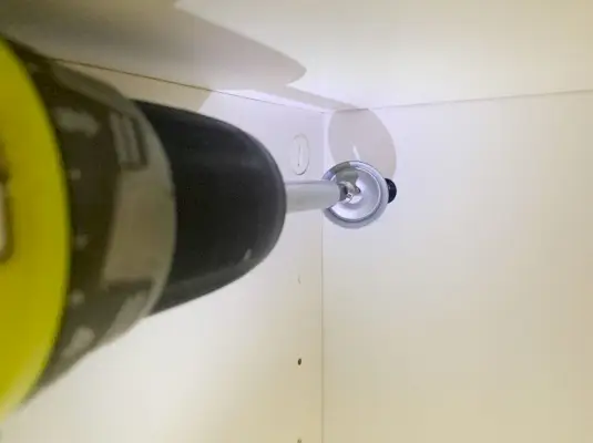 Schroevendraaier die een schroef installeert om de Ikea Besta-kast aan de muur te bevestigen