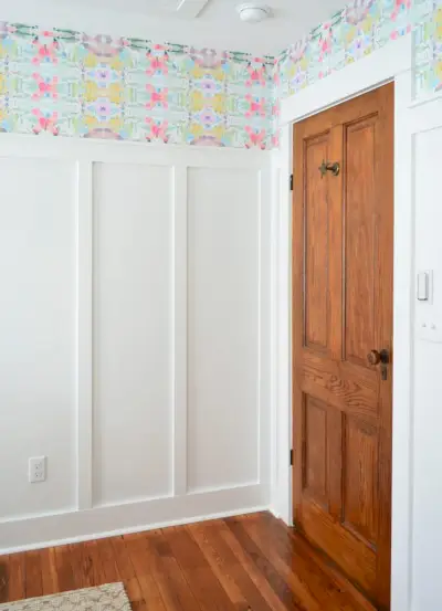 Houten deur in de kamer met wit bord en lat en kleurrijk schil- en plakbehang