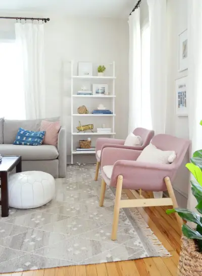 Roze Ikea-stoelen en open boekenkast in de woonkamer van het strandhuis