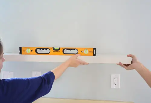 een niveau gebruiken om de plaatsing van Ikea-zwevende planken op de keukenmuur te markeren