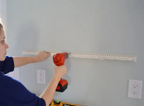 metalen ophangbeugel voor Ikea-zwevende plank bevestigen met behulp van een boormachine om deze aan de keukenmuur te schroeven