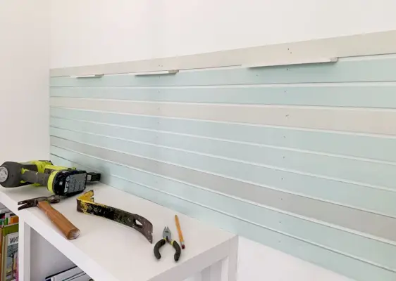 Eerste deel van geverfde houten roosterstrips die met behulp van afstandhouders aan de muur zijn bevestigd