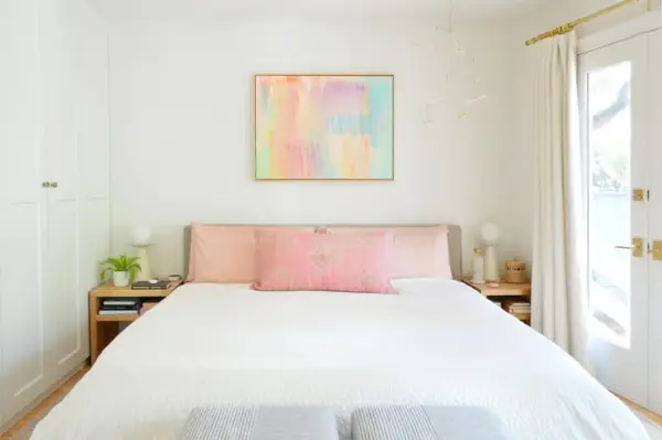 Lichte moderne slaapkamer met kingsize platformbed en kleurrijke abstracte schilderkunst