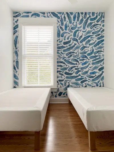 Kleine kamer met Peel-and-Stick-muurschildering van een blauwe vinvis en 2 eenpersoonsbedden