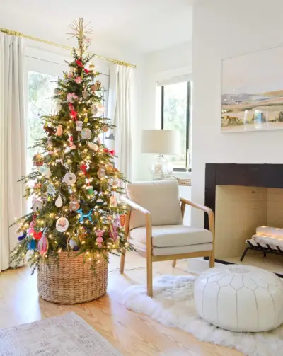 Kerstboom in geweven mand bij open haard