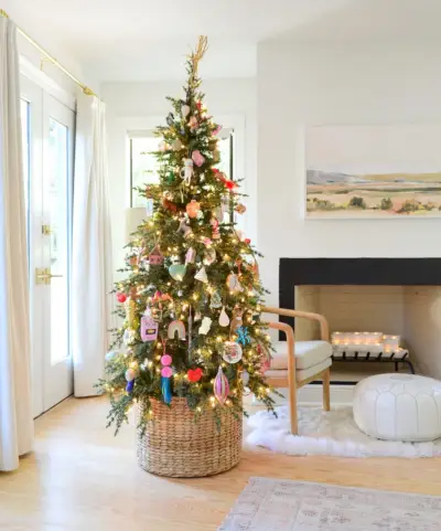 Geweven mand aan de voet van de kerstboom met kleurrijke ornamenten