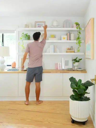 John reikt naar de bovenste plank van drie Ikea-planken zonder zwevende planken