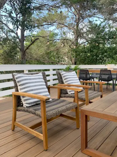 Twee gevlochten en houten loungestoelen voor buiten met grote gestreepte kussens