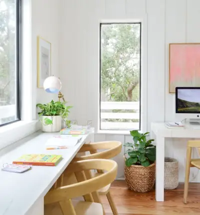 Kinderkunstbureau onder raam met computerwerkstation op de achtergrond