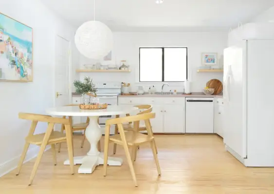 Minimale keuken met witte kasten, voetstuktafel en globe-hanglamp met houten stoelen