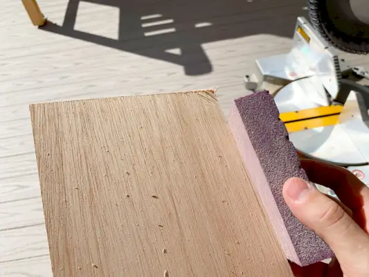 Ruwe randen van houten paneelstrips schuren met een schuurblok