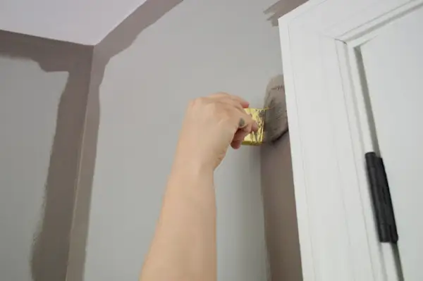 Hand met een klein penseel om de muren in de logeerkamer Sparrow te omranden