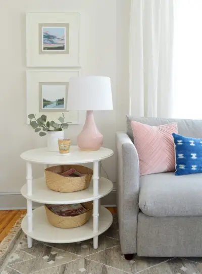 ronde witte bamboe bijzettafel met drie niveaus, roze lamp en grijze bank