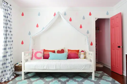 Meisjesslaapkamer met kleurrijke regendruppelmuurschildering rond luifel Daybed met open kastdeur