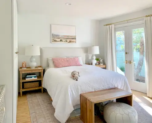 Slaapkamer met roze tapijt met openslaande deuren naast wit bed