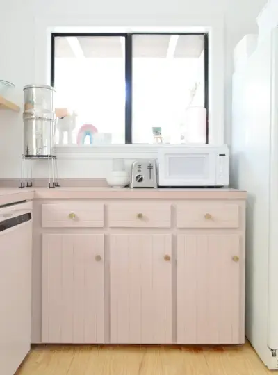 Keuken met paarse kasten en raam boven de toonbank