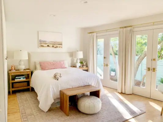 Slaapkamer met roze tapijt met openslaande deuren naast wit bed