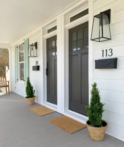 Duplex voorporch vanuit een hoek met deurmatten, plantenbakken en banken in dezelfde kleur