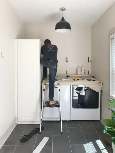 John leunt over de bovenkant en laadt de sluitring om de plankbeugels vast te schroeven