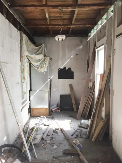 vóór foto van wasruimte met rottende muren en plafonds