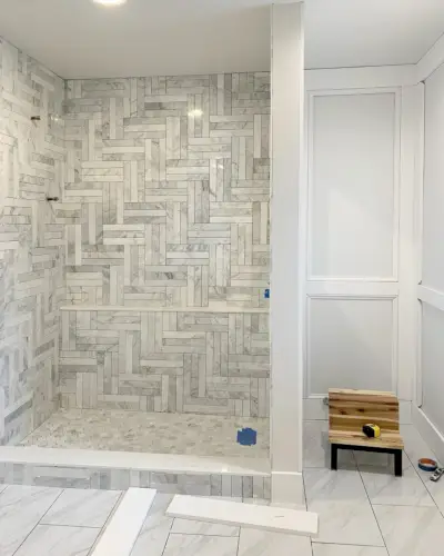 Ongeverfd decoratief wandlijstwerk in de hoofdbadkamer met betegelde marmeren douche