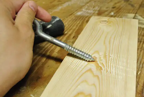 Schraap een cursusschroef over een nieuw houten bord om een verontrustend effect te creëren voor een doe-het-zelf-project