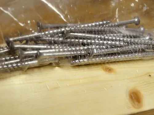 close-updetail van een plastic zak gevuld met grove schroeven die worden gebruikt om een meubelproject met een verweerde houtlook te creëren