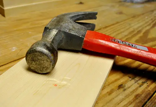met de hamer tegen een nieuw withouten bord slaan om het er oud, versleten en hergebruikt uit te laten zien
