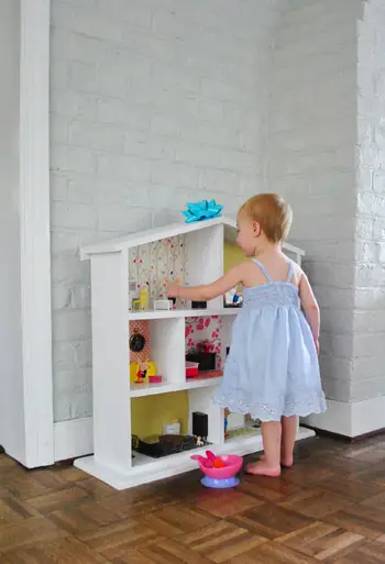 Peutermeisje speelt met poppenhuis gemaakt door ouders