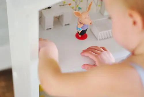 Bovenaanzicht van klein meisje spelen met zelfgemaakte DIY houten moderne poppenhuis