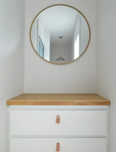 Ikea Malm-dressoir met slagersblok en leren trekjes onder ronde spiegel