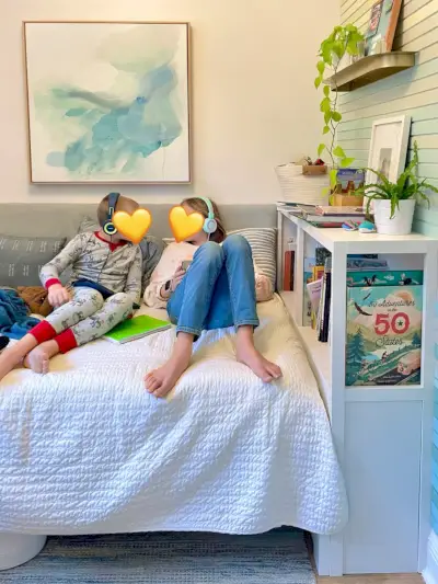 Ingebouwde boekenkast in kleine kinderkamer met twee kinderen op bed