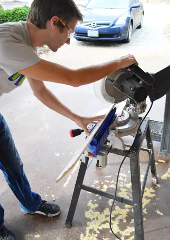 John gebruikt een verstekzaag om een snede in de kroonlijst te maken