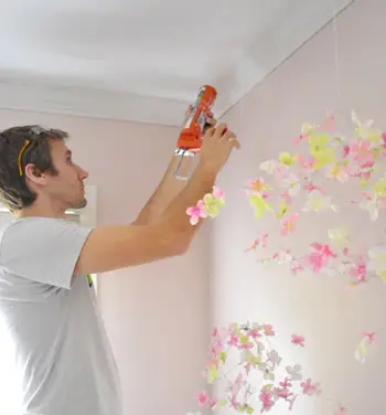 John voegt kit toe tegen het plafond waar de kroonlijst een kleine opening heeft