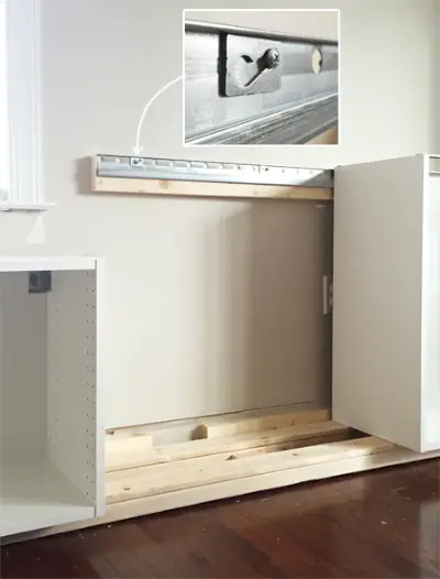 detail van hoe Ikea Sektion-kasten aan de metalen wandrail worden bevestigd met behulp van een schroef en een ring