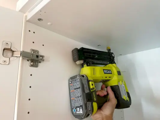 Spijker het steunstuk aan de bovenkant van de Ikea-kledingkast met behulp van een spijkerpistool