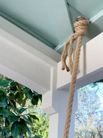 Touw geknoopt rond schroefooghaak in plafond van overdekte veranda