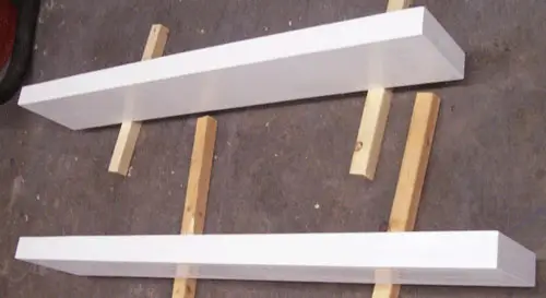 DIY-zwevende planken worden ondersteund en wit geverfd voordat ze worden opgehangen