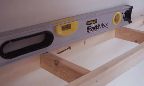 houten frame aan de muur bevestigen met behulp van een niveau voor zwevende DIY-planken