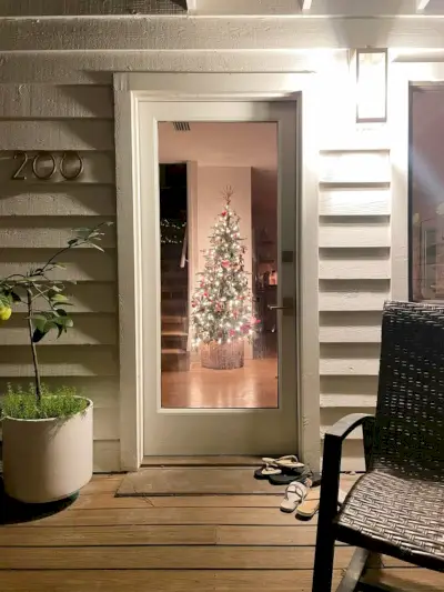 Uitzicht op de kerstboom in de keuken via de voordeur 's nachts