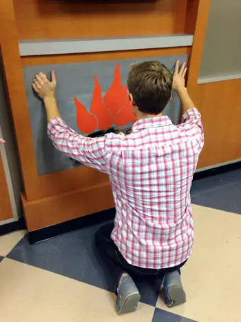 John plaatst zelf een nephaard op de mantel in de wachtkamer van het kinderziekenhuis