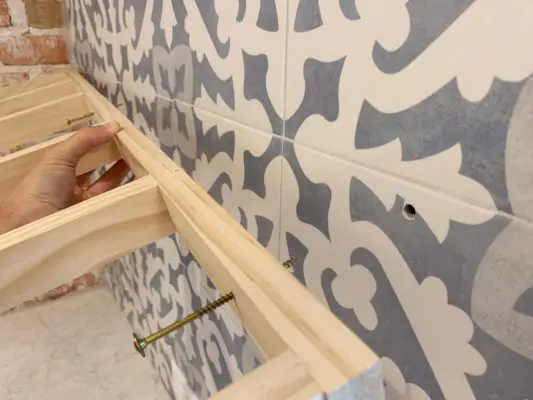 Gaten in de tegelwand waar de steunbeugel voor de plank wordt geplaatst