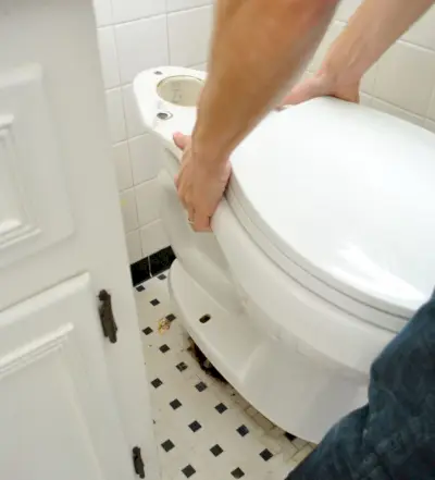 John plaatst een nieuwe toiletpot op de grond