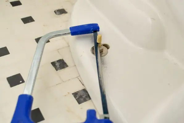 Ijzerzaag die overtollige boutlengte op nieuw toilet verwijdert
