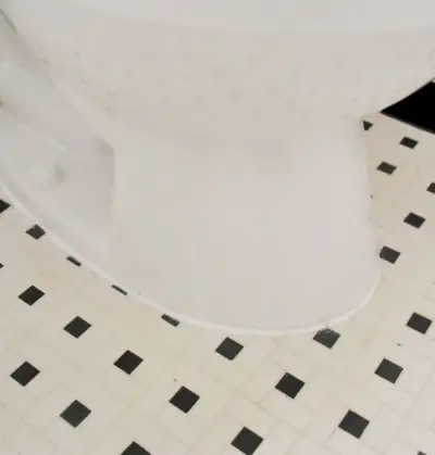 Lijn van witte kit rond de basis van het geïnstalleerde toilet
