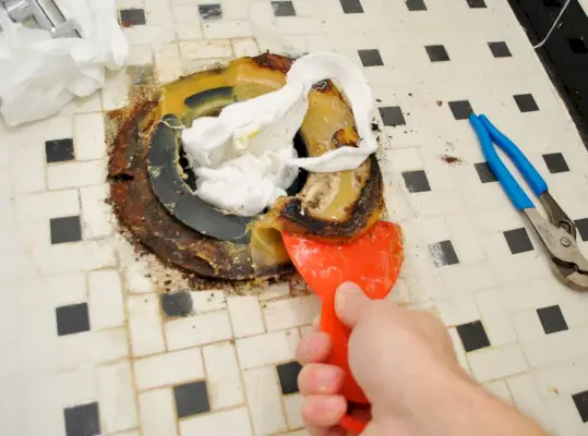 Oude wasring van de badkamervloer schrapen tijdens toiletinstallatie